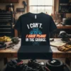Black t-shirt with white and red text "I CAN'T. I HAVE PLANS IN THE GARAGE." featuring a blue engine graphic