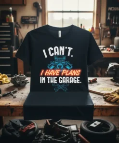 Black t-shirt with white and red text "I CAN'T. I HAVE PLANS IN THE GARAGE." featuring a blue engine graphic