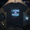 Black t-shirt with "I COME IN PEACE" in neon blue and pink, surrounded by circuit board lines and small UFO