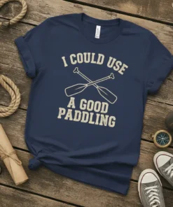Navy blue t-shirt with "I Could Use A Good Paddling" text and crossed canoe paddles graphic in cream