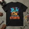 Black t-shirt with "I DO ALL MY OWN STUNTS" text and graphic of a superhero-style motorcycle rider jumping over two