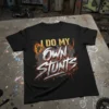 Black t-shirt with yellow and white text "I DO MY OWN STUNTS" and a flaming motocross rider graphic