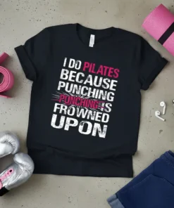 I Do Pilates Because Punching Is Frowned Upon quote on a black t-shirt, with pink and white distressed typography