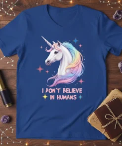 White unicorn with rainbow mane and "I Don't Believe In Humans" text on a blue t-shirt, surrounded by stars