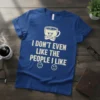 I DON'T EVEN LIKE THE PEOPLE I LIKE funny coffee quote on a blue t-shirt with a grumpy coffee cup