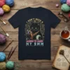 Black cat with knitting supplies and text "I DON'T NEED A LICENSE TO CARRY MY 9MM" on a navy t-shirt