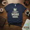 Navy t-shirt with distressed text "I DON'T WORK HERE." and a graphic of a clipboard with tools