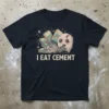 I Eat Cement quote with a cartoon ghost eating a brick and cement bags on a dark t-shirt
