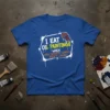 I Eat Oil Paintings When Security Guards Aren't Looking humorous quote on a blue t-shirt, art supplies in background