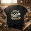 Black t-shirt with "I Eat Raw Cookie Dough I'm Such A Rebel" text in distressed vintage font, featuring decorative swirls