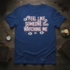 I Feel Like Someone Is Watching Me quote on a dark blue t-shirt with creepy eye graphics