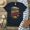 I FINALLY FOUND MY CALLING RETIREMENT text design with sunset and palm trees graphic, on a black t-shirt