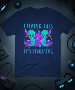 T-shirt design with text "I FOUND THIS IT'S VIBRATING," featuring two cute aliens holding black cats with planets and crystals