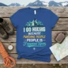 I Go Hiking Because Punching People Is Frowned Upon quote on a blue t-shirt with mountain graphics