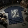 Dark navy t-shirt with distressed white text "I HATE PEOPLE AND BRAS" inside an ornate frame