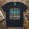 I Have Two Titles Dad & Grandpa And I Rock Them Both quote on a navy t-shirt, featuring bold blue