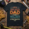 I Have Two Titles Dad And Welder & I Rock Them Both quote on a black t-shirt, featuring distressed orange