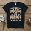 I Have Two Titles Mom and Nini And I Rock Them Both quote on a black t-shirt, featuring decorative lettering
