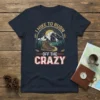 I Hike To Burn Off The Crazy quote on a dark navy t-shirt with a hiking boot, mountains, and sun