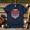 I HIT 100 DAYS OF SCHOOL text with baseball graphics on a navy blue t-shirt