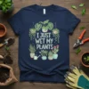 Navy blue t-shirt with the text "I JUST WET MY PLANTS" surrounded by various potted and hanging houseplants and a