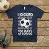 T-shirt featuring "I Kicked 100 Days of School" text with a soccer ball graphic and tally marks
