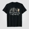 I like my books spicy & my coffee icy quote on a black t-shirt with a stack of books and