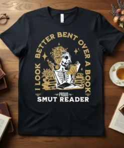 Black t-shirt with gold text: "I Look Better Bent Over A Book Proud Smut Reader", featuring a skeleton reading a