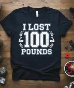 I LOST 100 POUNDS text with muscle graphics on a navy t-shirt, celebrating weight loss achievement