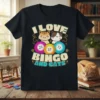 I LOVE BINGO AND CATS text with cartoon cats and bingo balls graphic on a black t-shirt