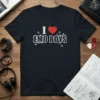 Black t-shirt with white text "I Love EMO BOYS" and a red heart graphic, surrounded by safety pins