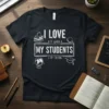I LOVE IT WHEN MY STUDENTS STOP TALKING quote in white distressed typography on a black t-shirt with school icons