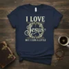I LOVE Jesus BUT I CUSS A LITTLE text on a navy t-shirt with a decorative wreath and cross graphic