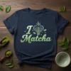 Navy blue t-shirt with "I Love Matcha" text and a heart made of a matcha whisk graphic, surrounded by leaves