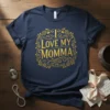 I Love My Momma text in ornate golden font surrounded by floral design on a navy blue t-shirt