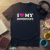 Retro pixelated "I Love My Roommate" text with a pink heart and gaming controllers graphic on a black t-shirt