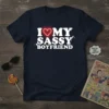 Navy blue t-shirt with white text "I Love My Sassy Boyfriend" and a red neon heart graphic, featuring a playful