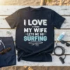I Love It When My Wife Lets Me Go Surfing text with a surfboard and wave graphic on a navy