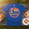 Blue t-shirt with "I Love Wieners" text, a rainbow heart, and hot dog graphics, part of a pride collection