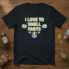 Funny "I Love To Smell Farts" text design with cartoon nose and clouds on a black t-shirt