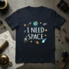 Navy blue t-shirt with "I NEED SPACE" in white text, surrounded by cartoon space graphics like planets, rockets, and astronauts