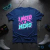I Need A Hero text in neon pink and teal on a navy blue t-shirt, featuring retro gaming graphics and