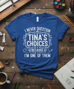 Blue t-shirt with white text: "I Never Question Tina's Choices Because I'm One of Them". Design includes art-related graphics like