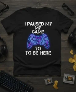 Black t-shirt with white text "I PAUSED MY MY GAME TO TO BE HERE" and a neon blue and purple