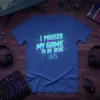 I Paused My Game To Be Here quote on a blue t-shirt with neon green and pink retro gaming graphics