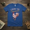 I RAISE TINY Dinosaurs text with a detailed rooster graphic on a royal blue t-shirt