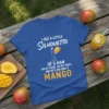 Blue t-shirt with white text "I See A Little Silhouetto" and a graphic of a man holding a mango, followed