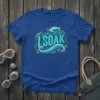 Blue t-shirt with "I SOAK" text in wavy turquoise font, surrounded by water graphics and aquatic plants