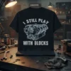 Black t-shirt with white text "I Still Play With Blocks" and a detailed engine block diagram graphic for mechanics