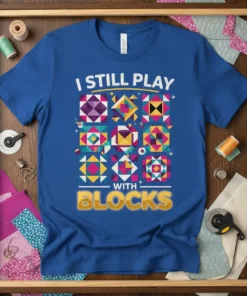 Blue t-shirt with "I Still Play With Blocks" text and colorful quilt block graphics